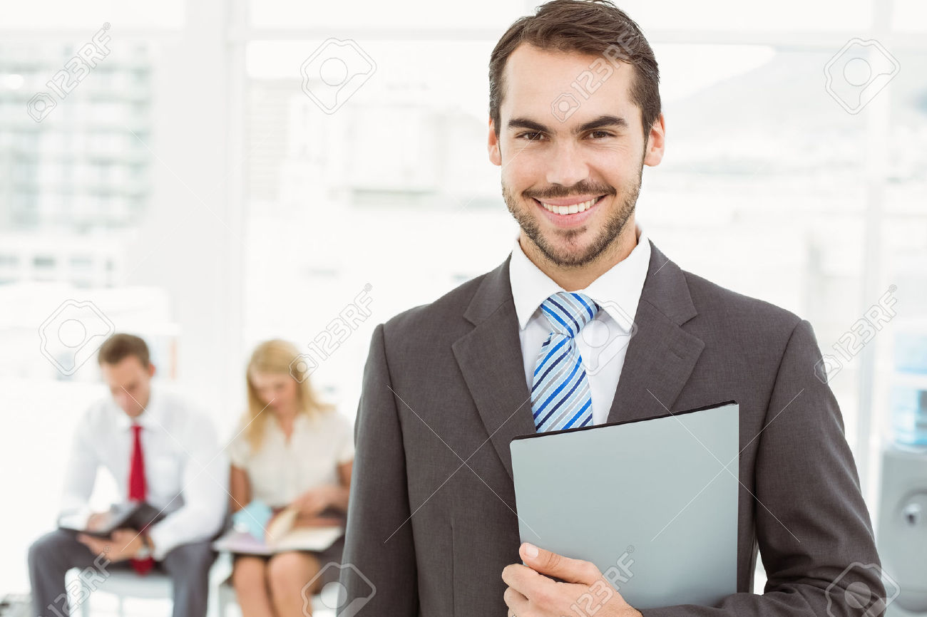 32789325-Portrait-of-businessman-against-people-waiting-for-job-interview-in-office-Stock-Photo