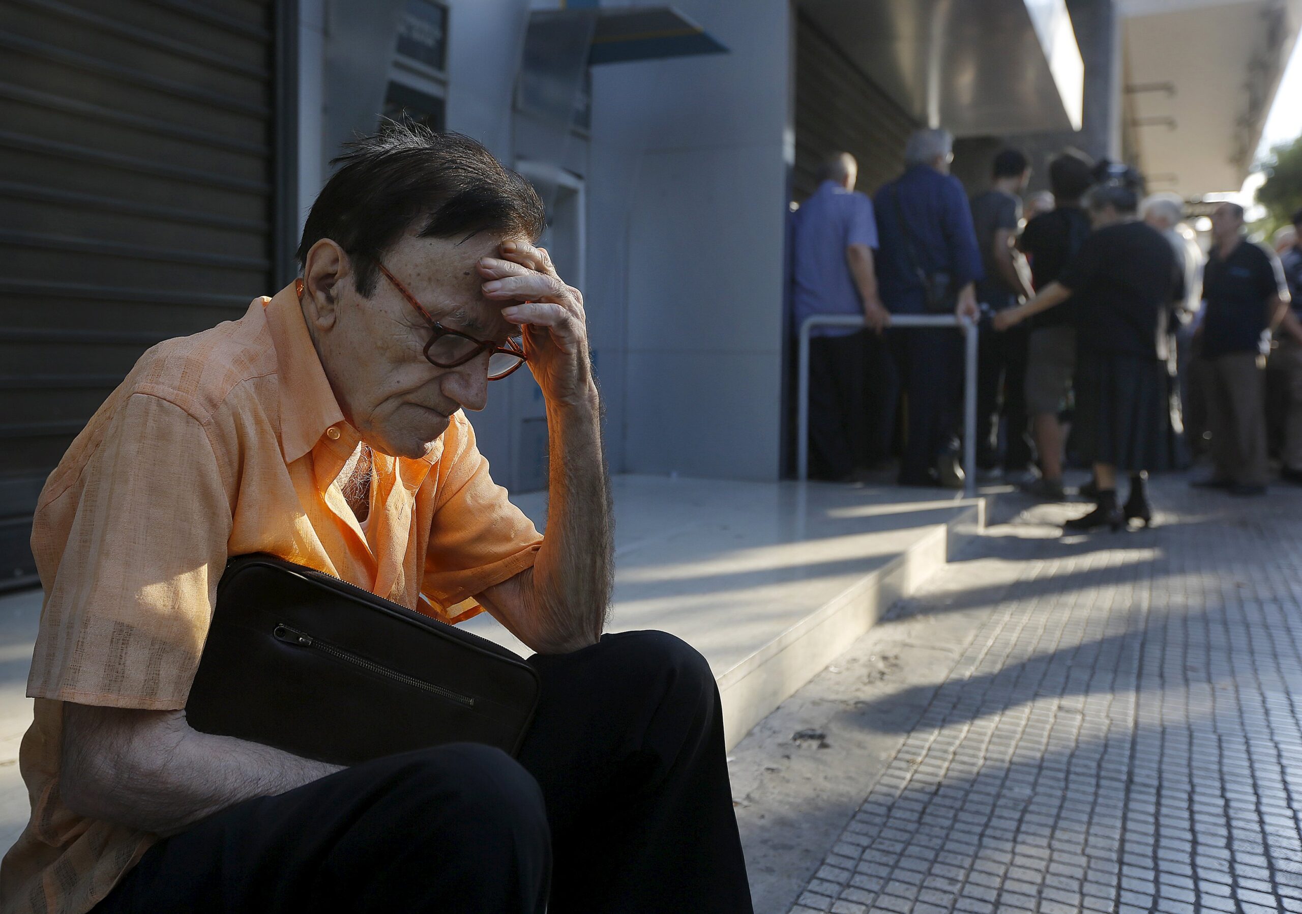 Giorgos, a 77-year-old pensioner from Athens, sits outside a branch of the National Bank of Greece as he waits along with dozens of other pensioners, hoping to get their pensions in Athens